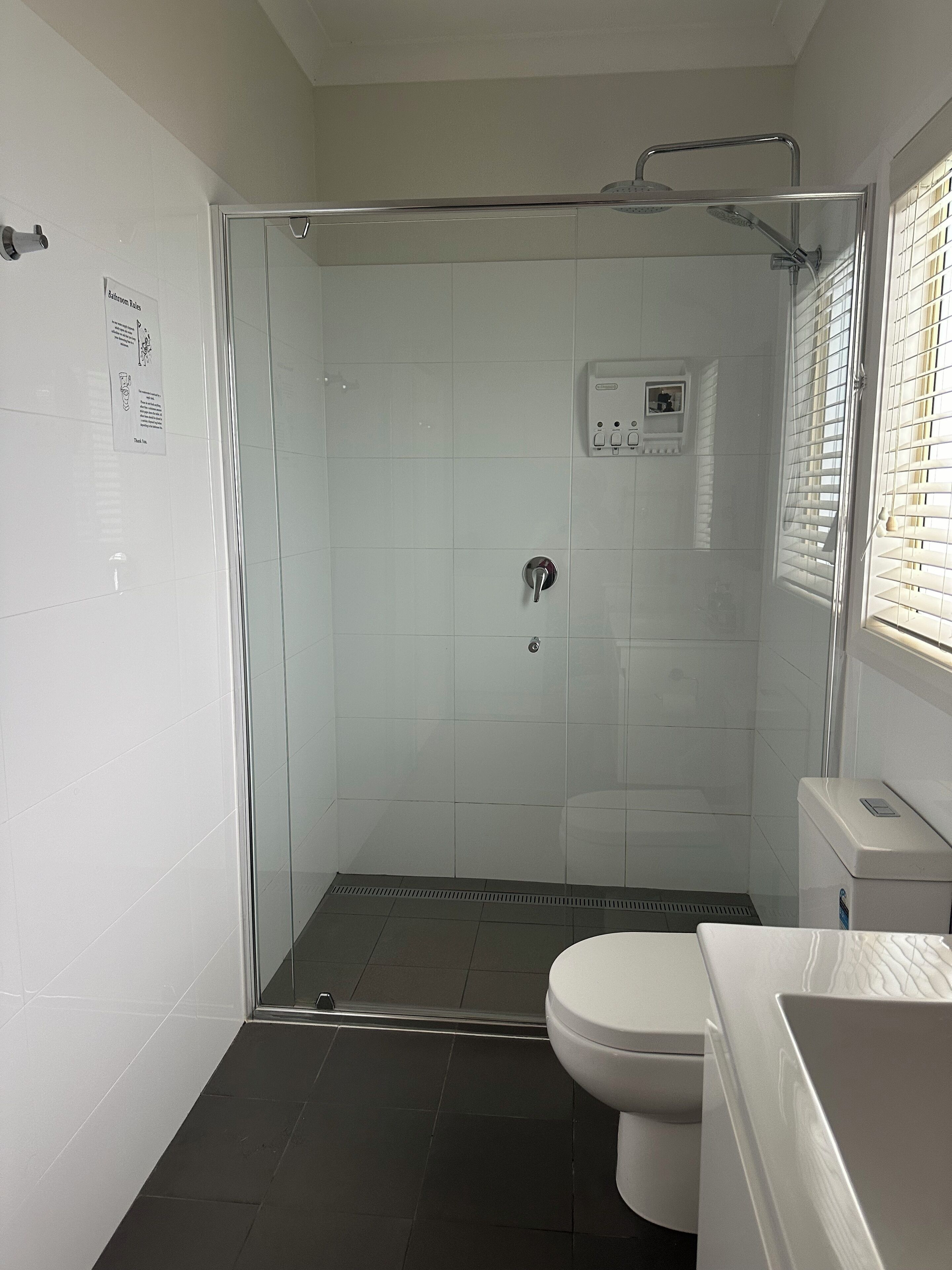Un baño con ducha de vidrio, inodoro y lavamanos.