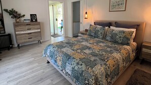Un dormitorio con una cama grande, un aparador, un radiador y una puerta que da a un balcón.