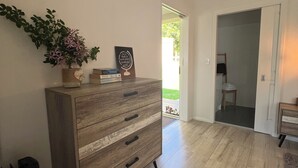 Un aparador de madera con cajones, una planta en maceta y una cita enmarcada en la pared.