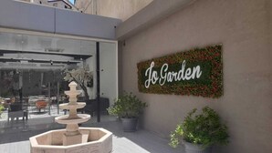 A courtyard with a stone fountain, outdoor seating, and a sign reading "Jo Garden". - JORDAN VIEW HOTEL (Amman)