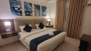 A hotel room with a large bed, two bedside tables with lamps, a wall-mounted power outlet, and three abstract paintings above the bed. - JORDAN VIEW HOTEL (Amman)