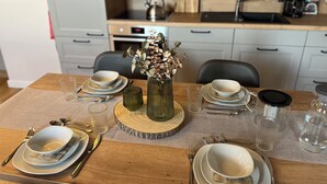 A dining table set with plates, bowls, cutlery, and a vase with dried flowers. - Über den Dächern von Braunlage - Urlaub zu Viert (Braunlage)