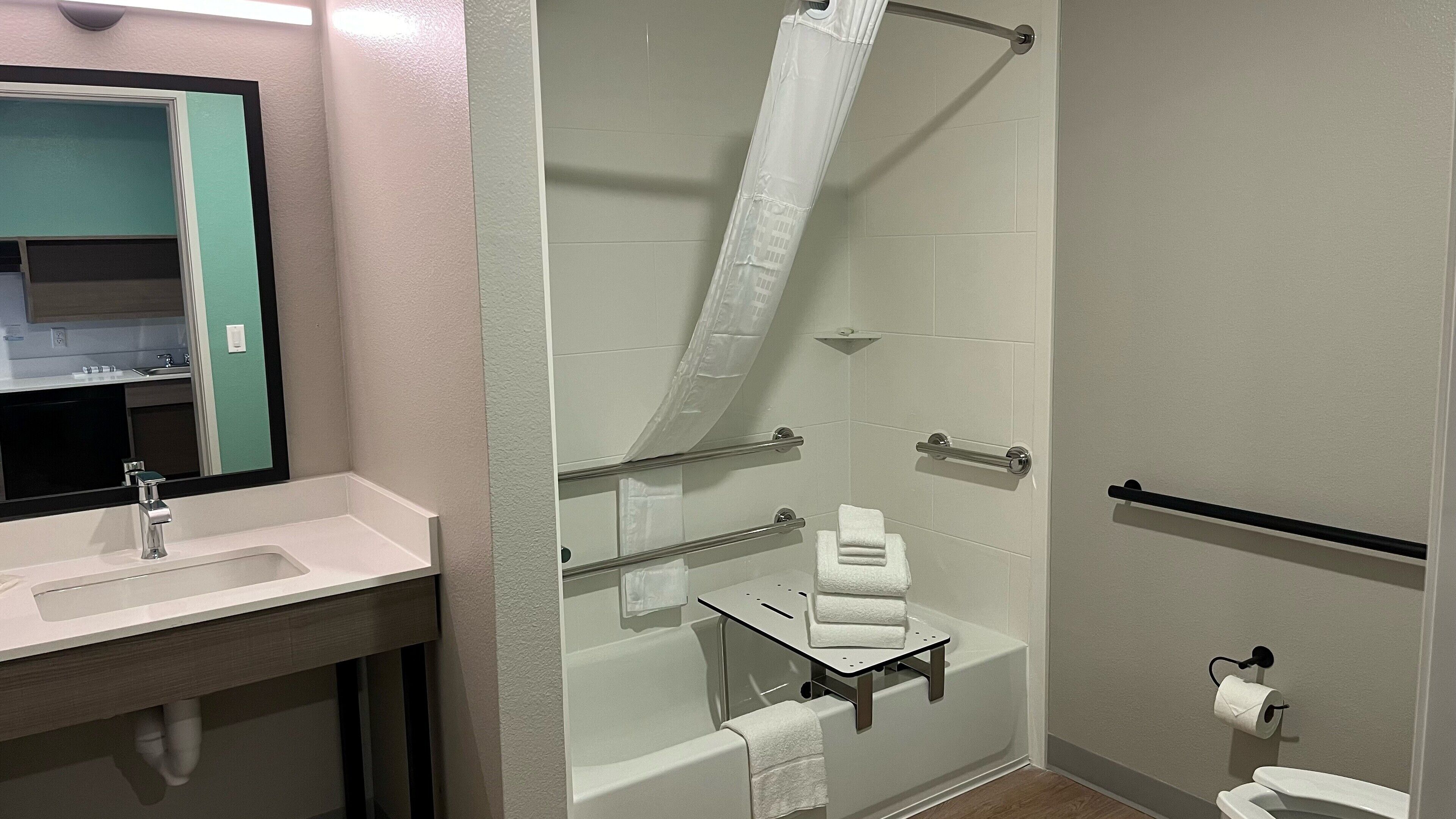 A bathroom with a sink, mirror, shower, and toilet.