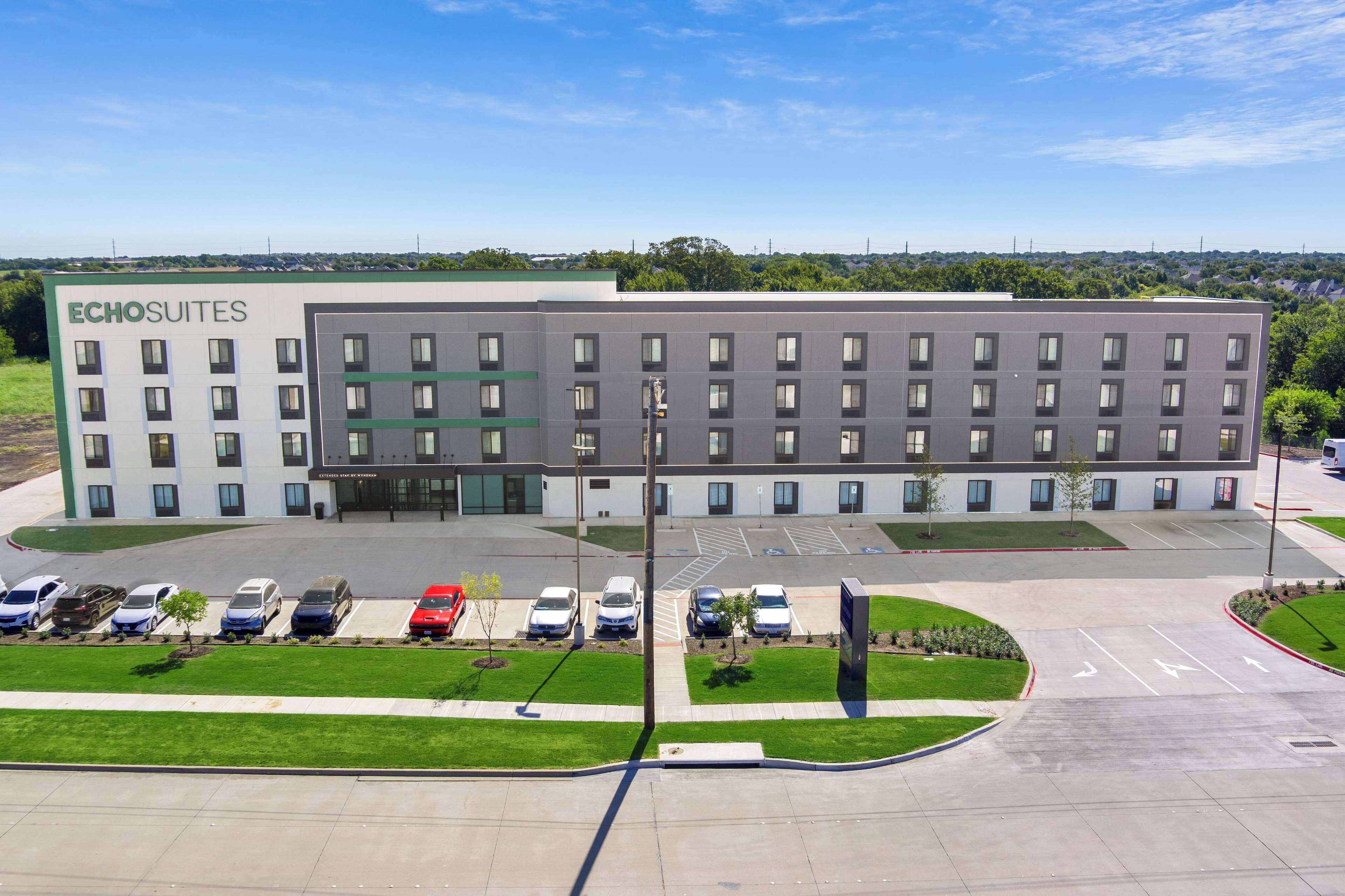 A modern hotel with a large parking lot and several cars parked in front.