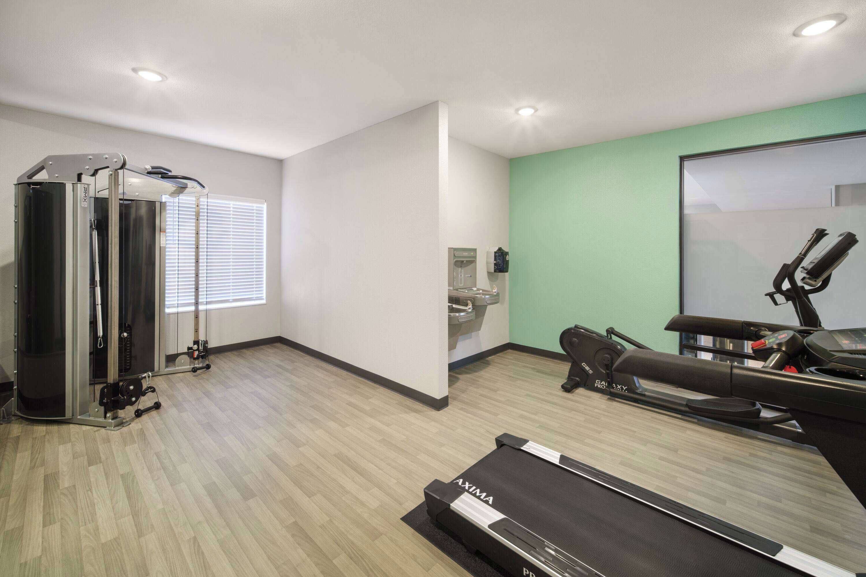 Ein Fitnessstudio mit Laufband, Kraftgeräten und Trainingsmatten.