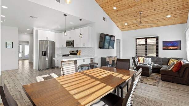 A spacious living area with a wooden dining table, a sofa, and a TV mounted on the wall. - Charming House & Cottage in Downtown Phoenix (Phoenix)