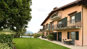 A two-story building with a balcony, outdoor seating, and a well-maintained lawn. - La Grolla del Garda - App. Giada (Manerba del Garda)