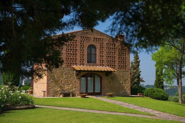 Un bâtiment en pierre avec un toit en tuiles, une fenêtre centrale en arc de cercle et un petit porche.