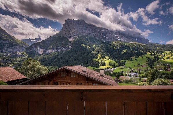 A wooden chalet with a view of a mountainous landscape and a prominent peak in the background.