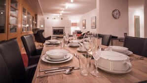 A dining area with a long wooden table set for a meal, surrounded by black chairs. - Apartment Breithorn Grindelwald (Grindelwald)