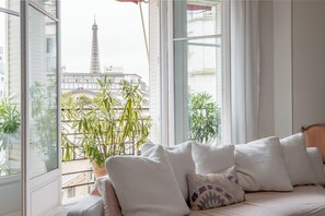 Une chambre avec un lit, une plante en pot et une vue sur la Tour Eiffel.