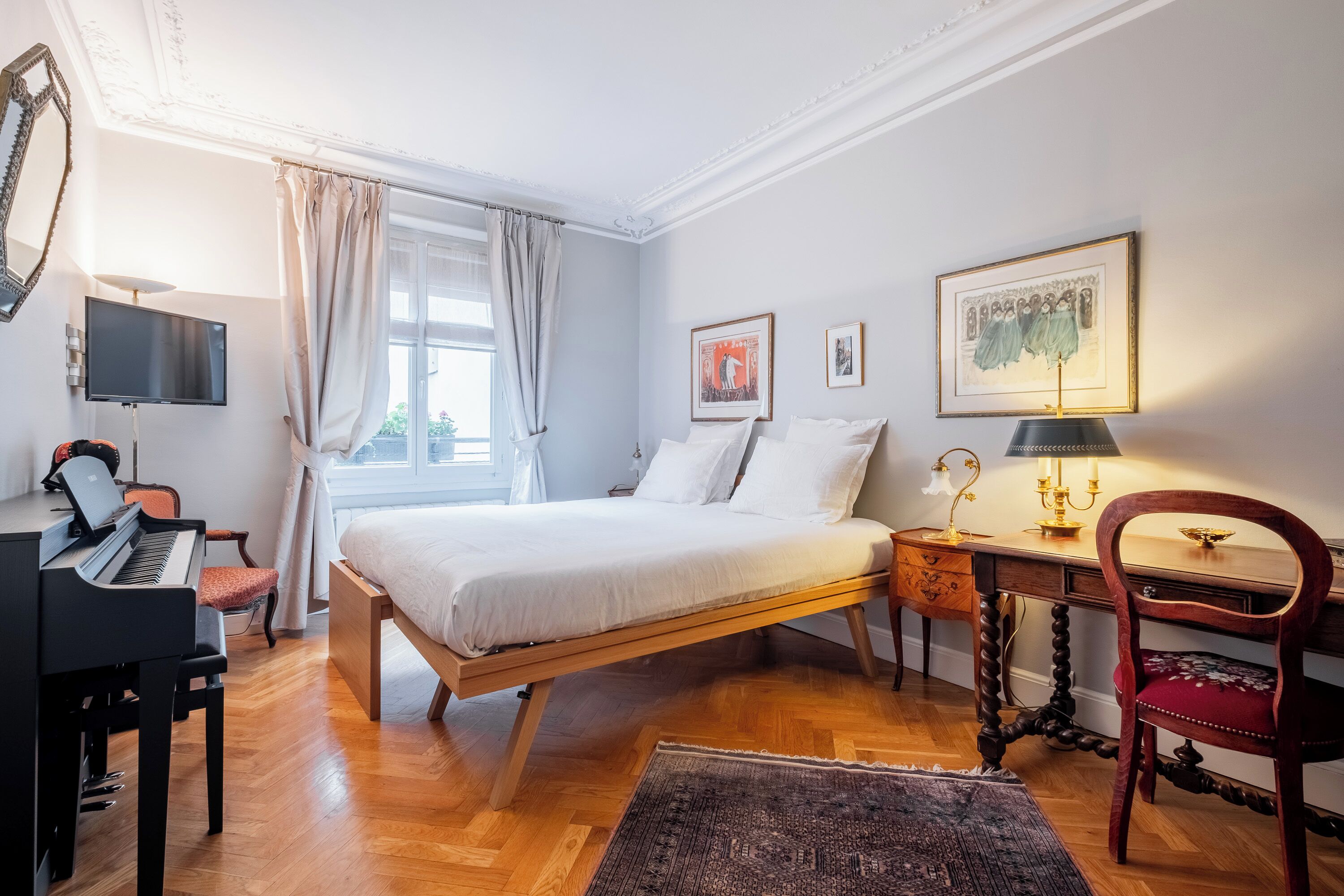 Een slaapkamer met een bed, een bureau, een stoel, een piano en een televisie.