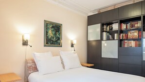 A bedroom with a bed, bedside tables, a bookshelf, and a painting on the wall. - Triumphant Design, by Veeve (Paris)