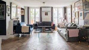 Ein modernes Wohnzimmer mit einem schwarzen Sofa, einem blauen Sessel und einem Glastisch.