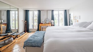 Ein Hotelzimmer mit einem großen Bett, Holzboden, einem Schreibtisch mit Stuhl, einem Spiegel und einem Fenster mit Vorhängen.