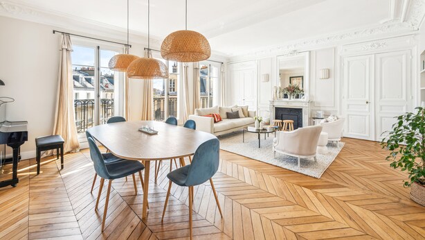 A spacious living room with a large wooden herringbone floor, a dining area with a round table and blue chairs, and a cozy seating area with a sofa and armchairs. - A Vision in White, by Veeve (Paris)