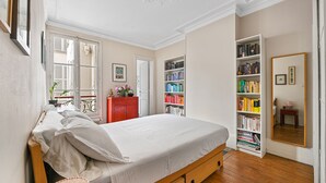 A bedroom with a bed, a bookshelf, a dresser, and a mirror. - Batignolles Gem, by Veeve (Paris)