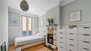 A bedroom with a bed, a dresser, a bookshelf, and a hanging light fixture. - Batignolles Gem, by Veeve (Paris)