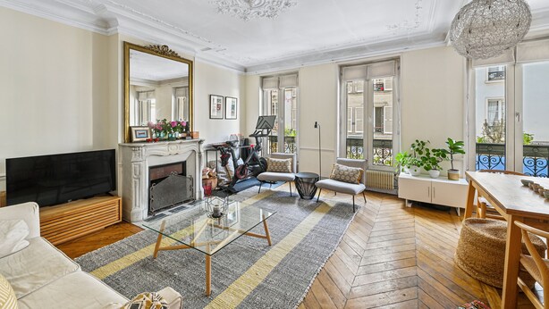 A living room with a fireplace, sofa, TV, and a dining area with a table and chairs. - Batignolles Gem, by Veeve (Paris)