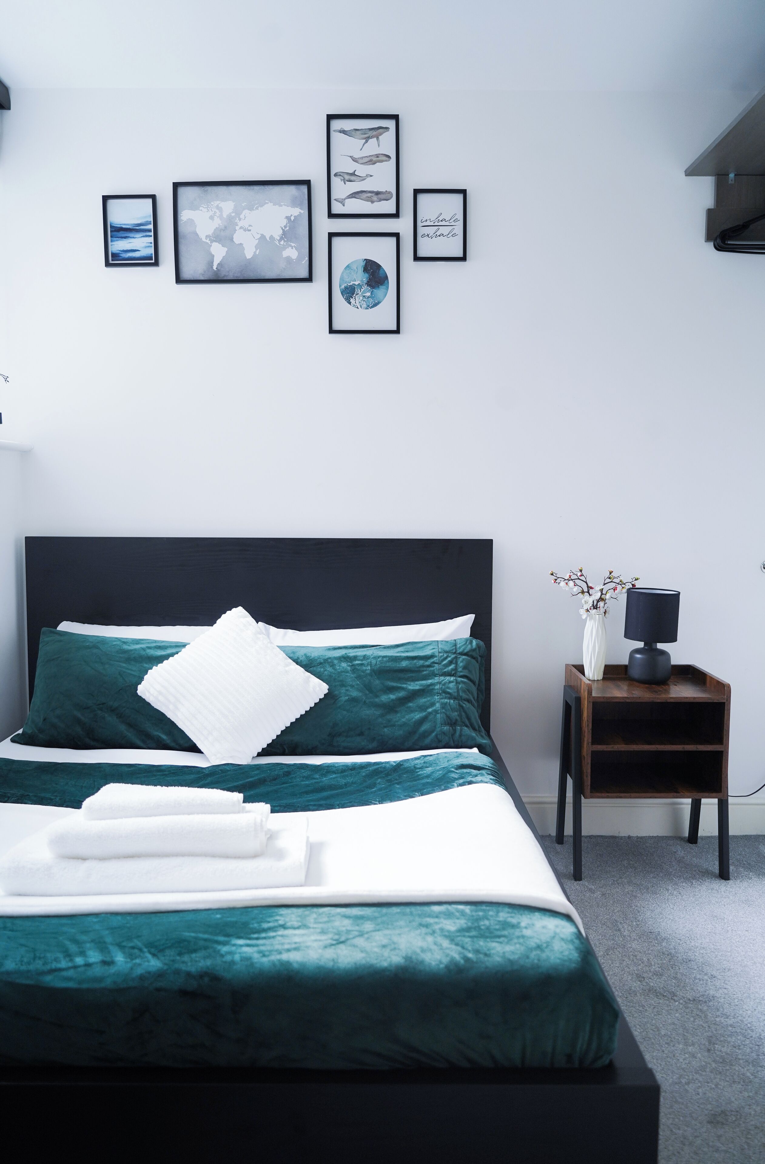 A neatly arranged bedroom with a bed, a nightstand, and wall-mounted artwork.