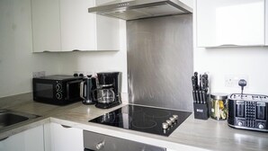 A modern kitchen with a microwave, coffee maker, toaster, and a stainless steel range hood. - 40percent off Monthly /2 Bedroom apt / City Centre (Swindon)