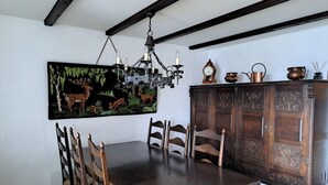 Ein Esszimmer mit Holztisch und -stühlen, einer Chandelier, einem Hirschgemälde und einer Holztruhe mit Dekorationen.