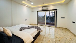 Une chambre à coucher comprenant un lit, un ventilateur de plafond, des luminaires encastrés, une porte-fenêtre coulissante et une vue sur l’extérieur.