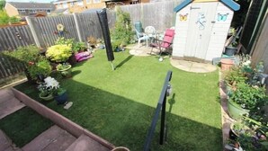 A backyard with a small shed, a lawn, and various potted plants.