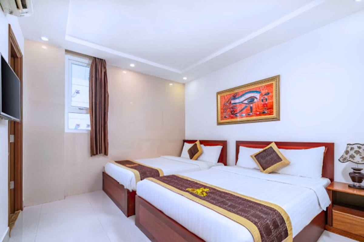 A hotel room with two beds, a television, a painting, and a window with curtains.