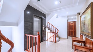 A hotel lobby with a staircase, wooden railing, a painting, and a reception desk. - Dubai Hotel (Da Nang)