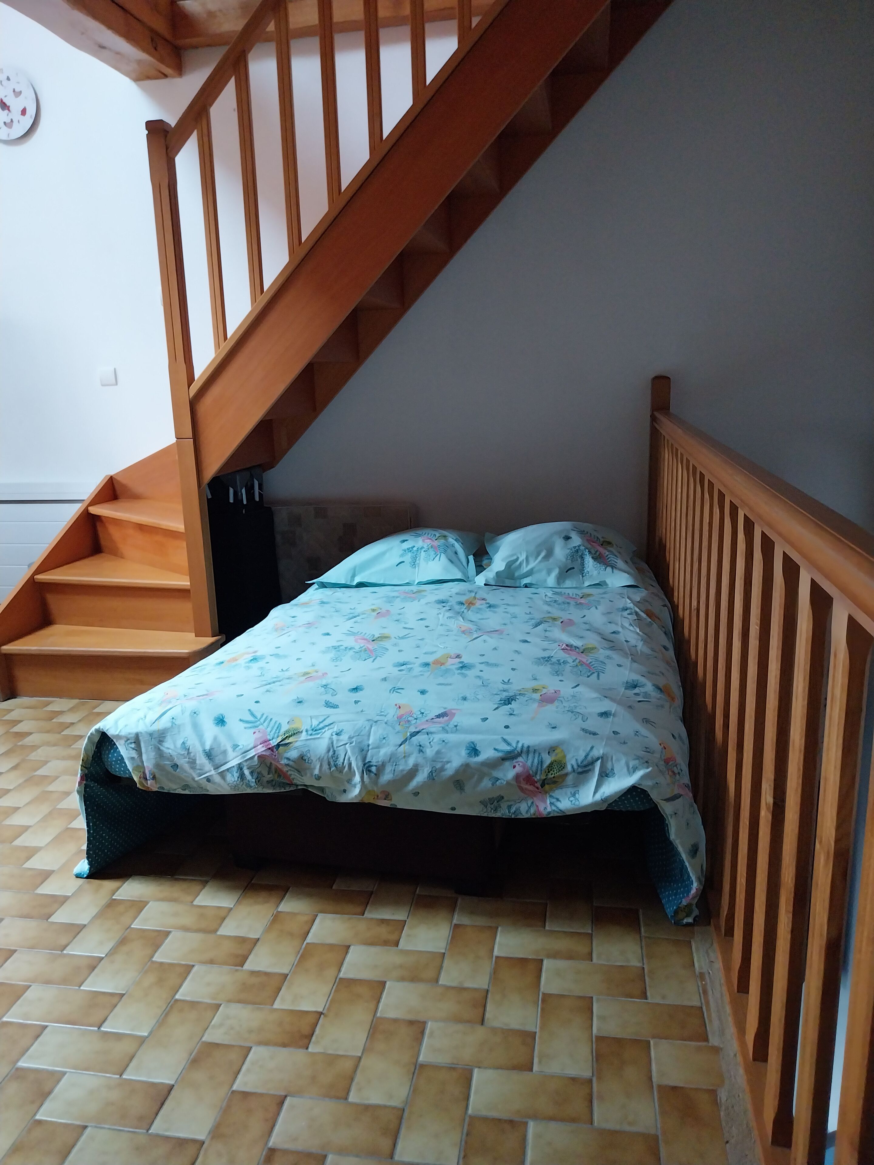 Een slaapkamer met een bed, een houten trap en een betegelde vloer.