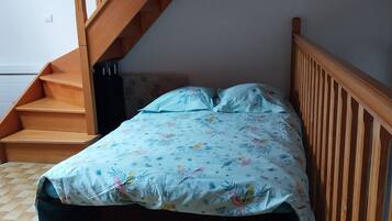 Een slaapkamer met een bed, een houten trap en een betegelde vloer.