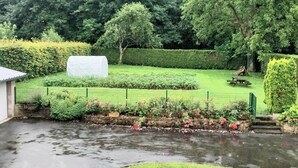 Un jardín con un estanque, setos bien cuidados y una mesa de picnic.