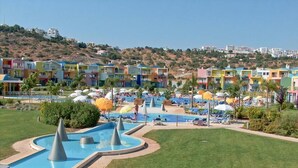 Un resort con piscina, lettini e edifici colorati sullo sfondo.