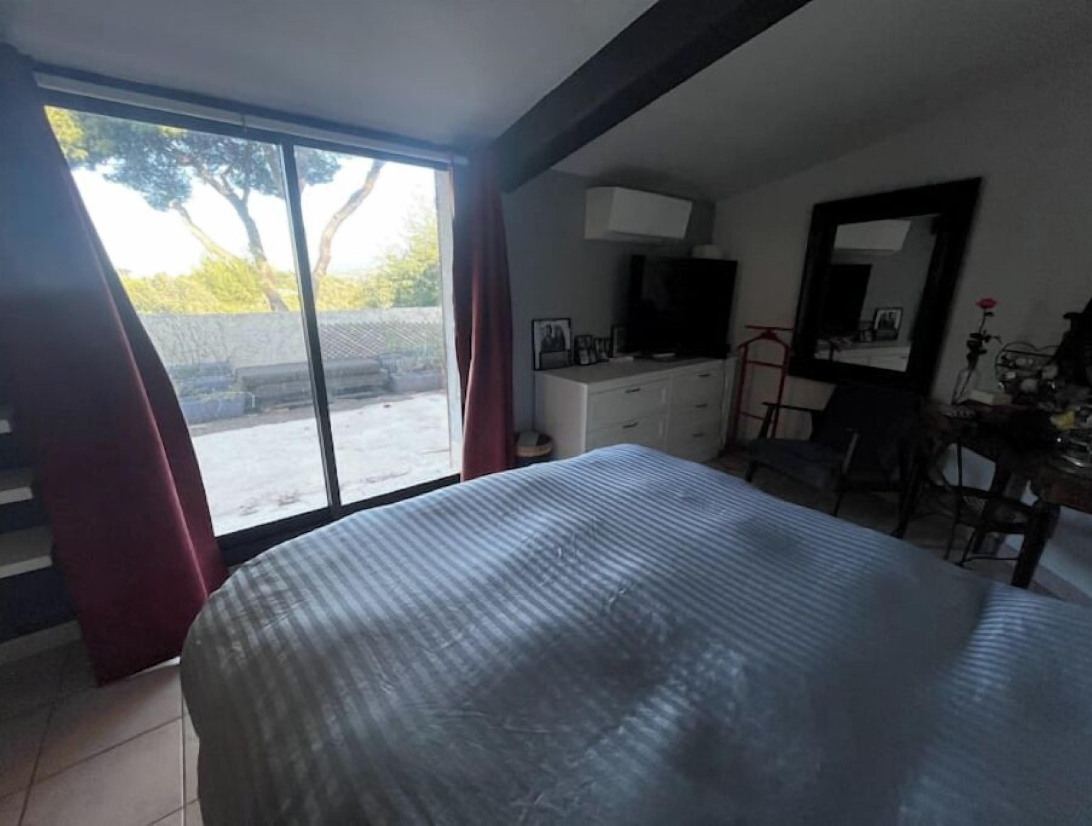 A bedroom with a large bed, a dresser, a desk, and a window with curtains.