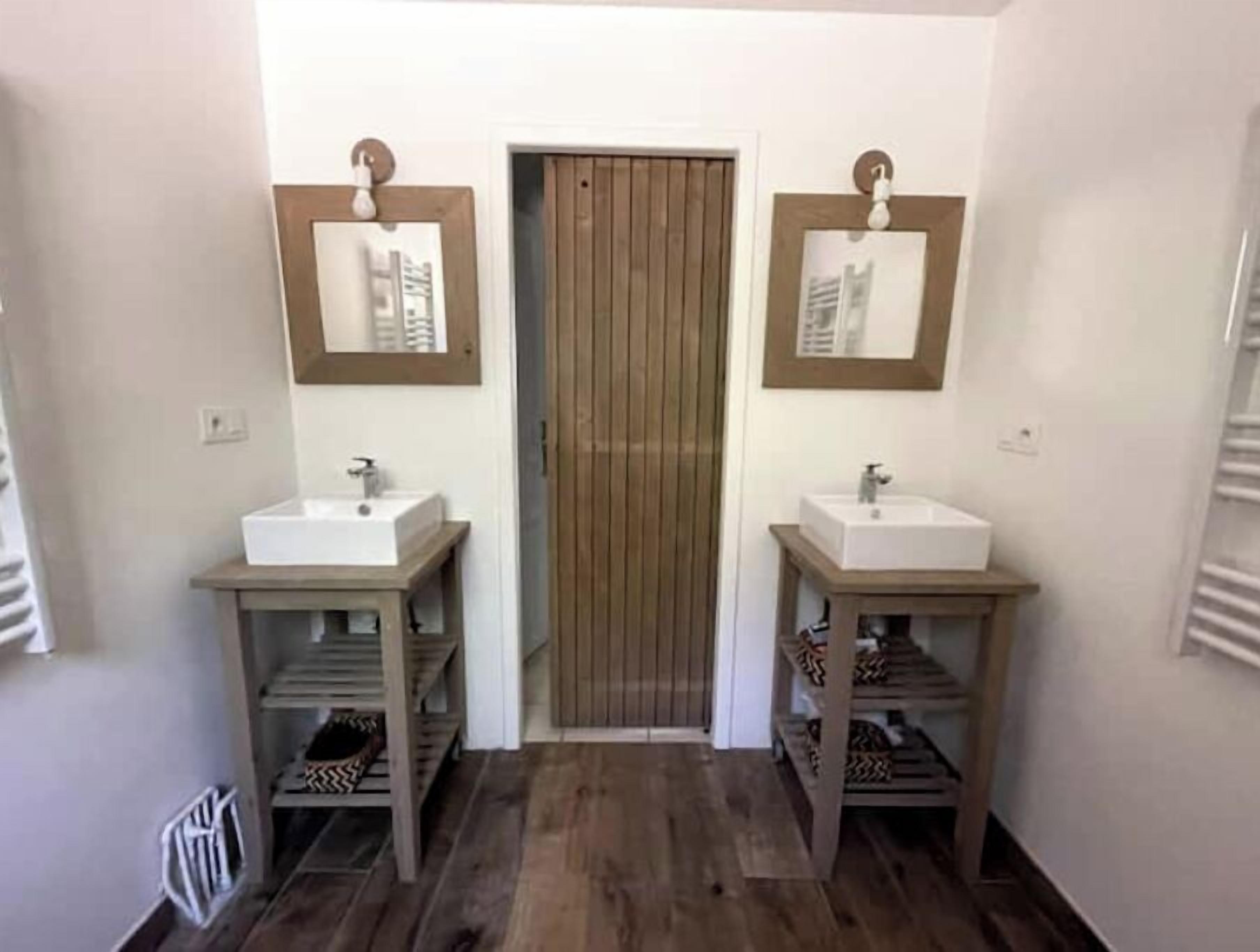 A bathroom with two sinks, wooden vanity units, and framed pictures on the walls.