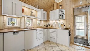 Een moderne keuken met witte kastjes, een houten plafond en een groot raam.