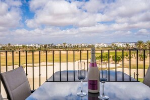 Un balcon avec une table, une bouteille de champagne et deux verres.
