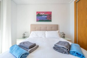 Une chambre d’hôtel avec un lit, deux tables de chevet, un tableau au mur et des serviettes sur le lit.