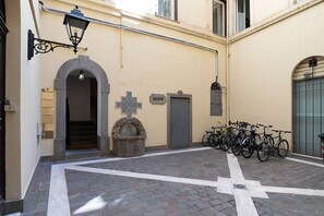 Ein Innenhof mit einer Steinsitzbank, einem Kreuz und abgestellten Fahrrädern.