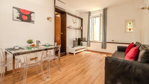 Un espacio de estar moderno con comedor, sofá y una escalera que sube a otro nivel.