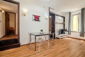 Una habitación moderna con una mesa de comedor de vidrio, sillas transparentes, una planta pequeña y un cuadro en la pared.