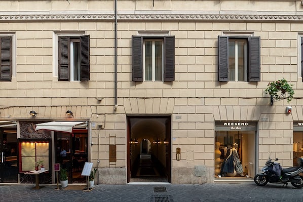 Ein Gebäude mit Schaufenster, einer Treppe zu einer oberen Ebene und einem abgestellten Roller.
