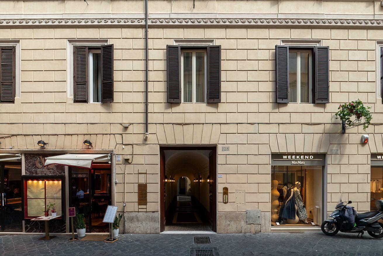 A building with a storefront, a staircase leading to an upper level, and a parked scooter.