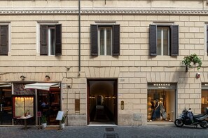 A building with a storefront, a staircase leading to an upper level, and a parked scooter.