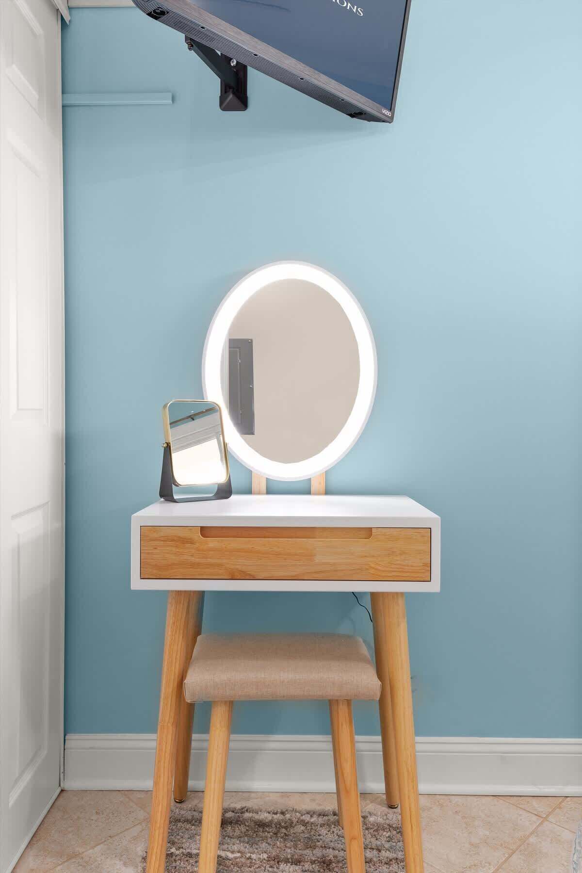 A vanity with a round mirror, a small table, and a stool.