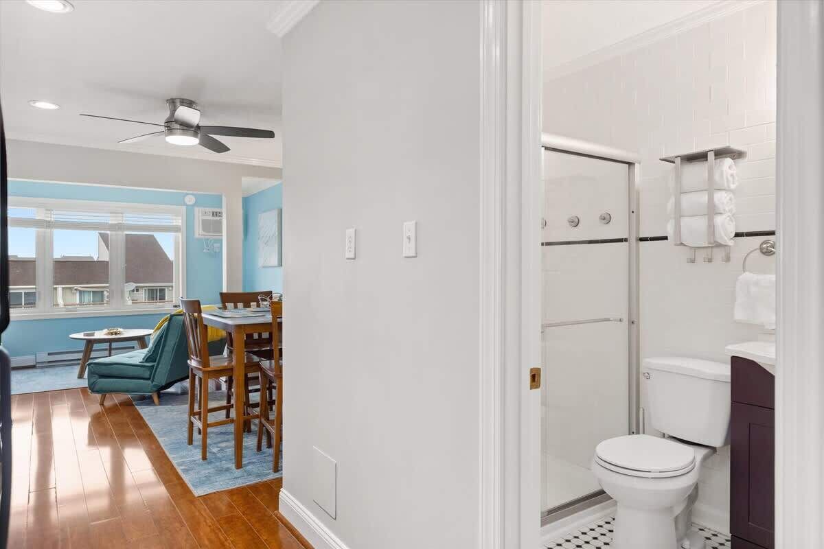 A modern bathroom with a glass shower enclosure, a white toilet, and a dark-colored vanity.