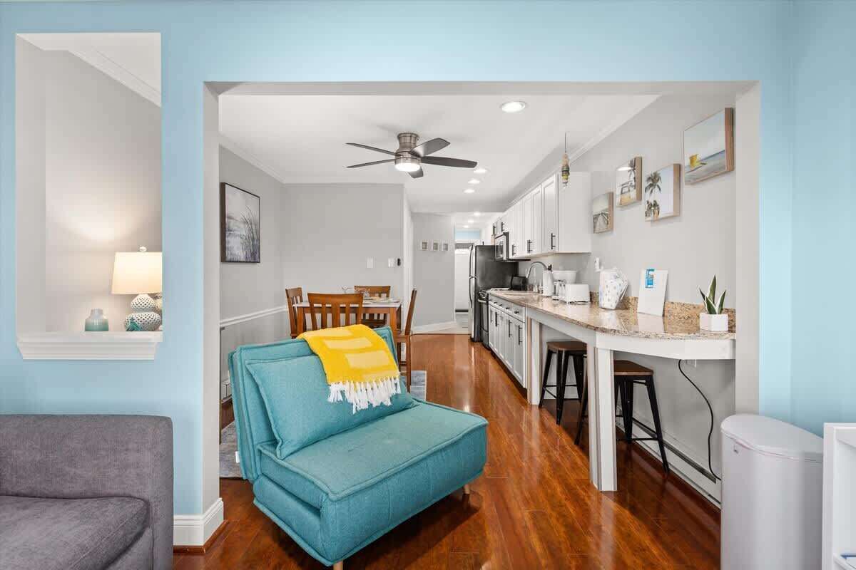 A modern kitchen with white cabinets, a central island, and a ceiling fan.