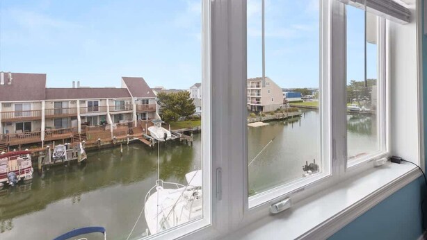 Vista desde una ventana sobre un canal con barcos y edificios.