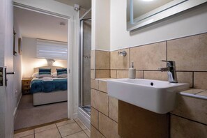 A bathroom with a white sink, a mirror, and beige tiled walls. - Modern, Dog friendly, 2 Bedroom Beach Front Apt. Central Newquay (Newquay Cornwall)